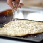 sprinkling parmesan on pissaladiere dough