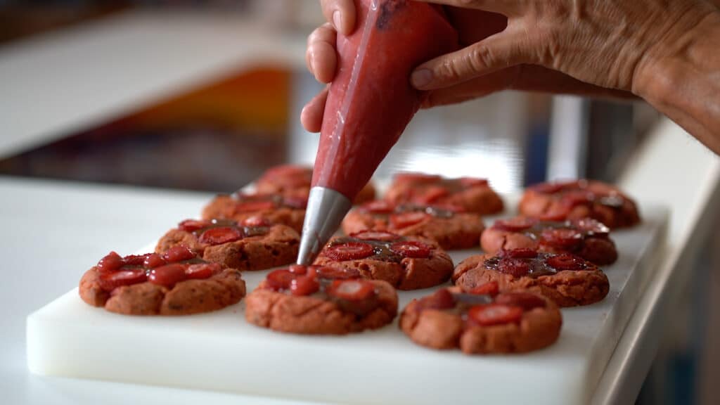 piping strawberry marmalade on cookies