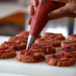 piping strawberry marmalade on cookies