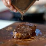 topping steak with pepper